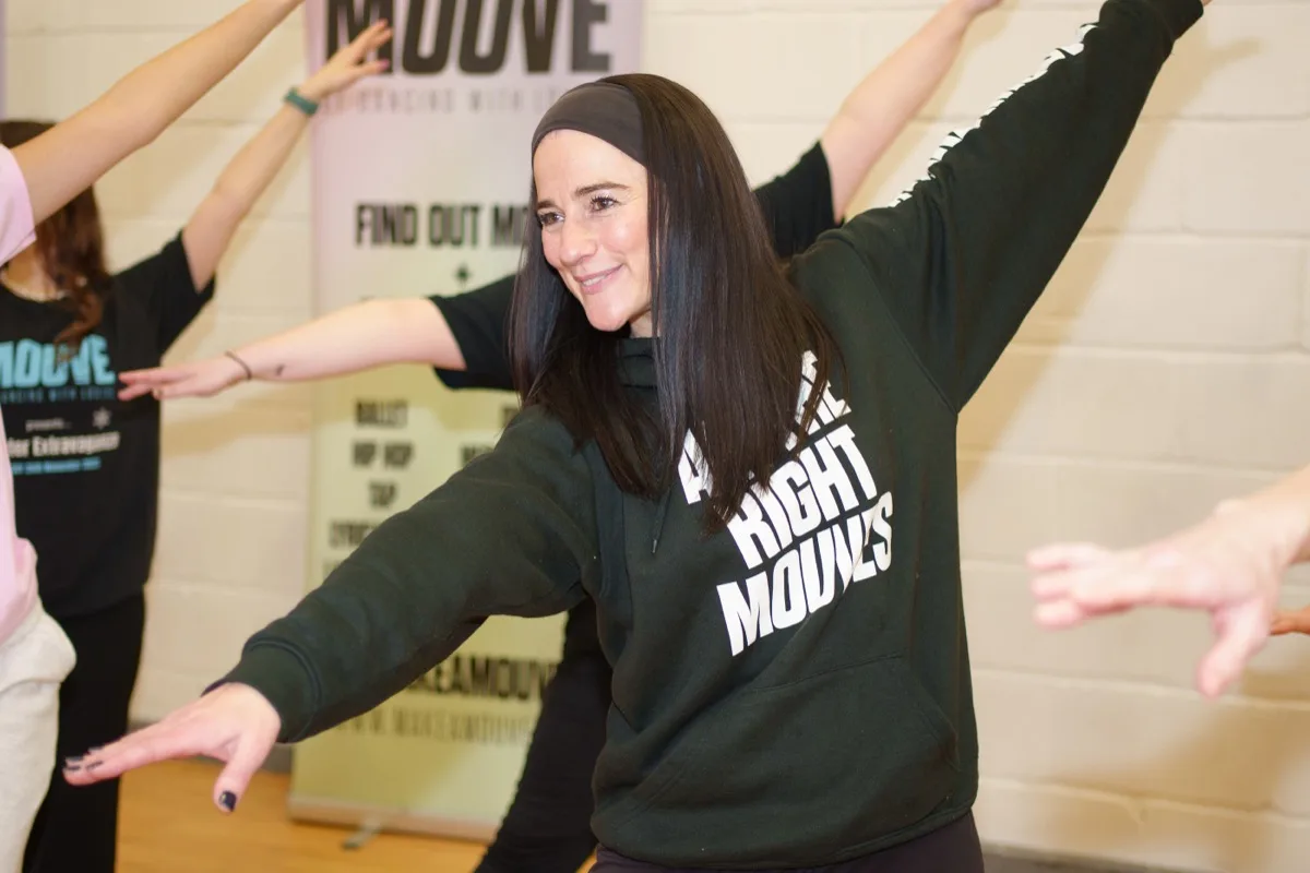 Louise Leach teaching a dance fitness class at MOUVE in North London, arms extended mid-move